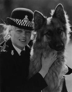 A person in uniform holding a dog

Description automatically generated